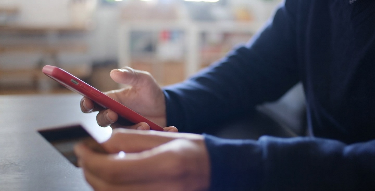 Gros plan sur une main tenant un smartphone affichant une interface d'application bancaire avec catégories de dépenses et suivi budgétaire